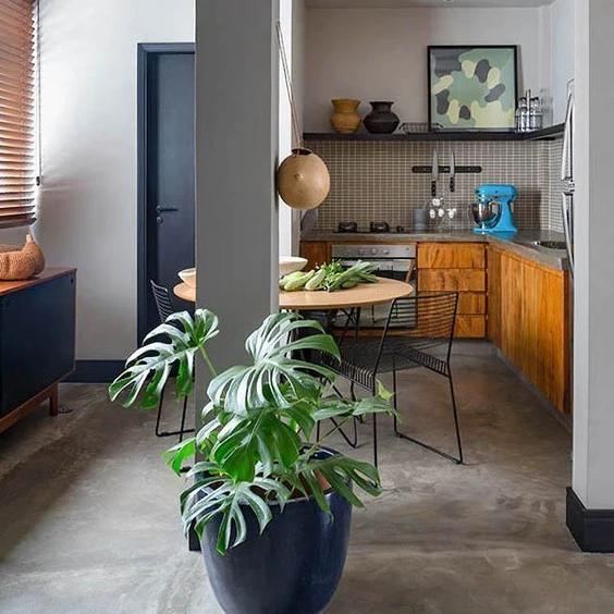 Imagem de um apartamento bem decorado com flores, mesa, bancada de cozinha e moldurada.